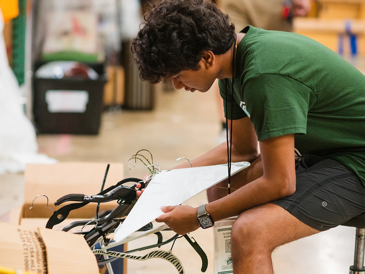 Student volunteer sorting clothes hangers