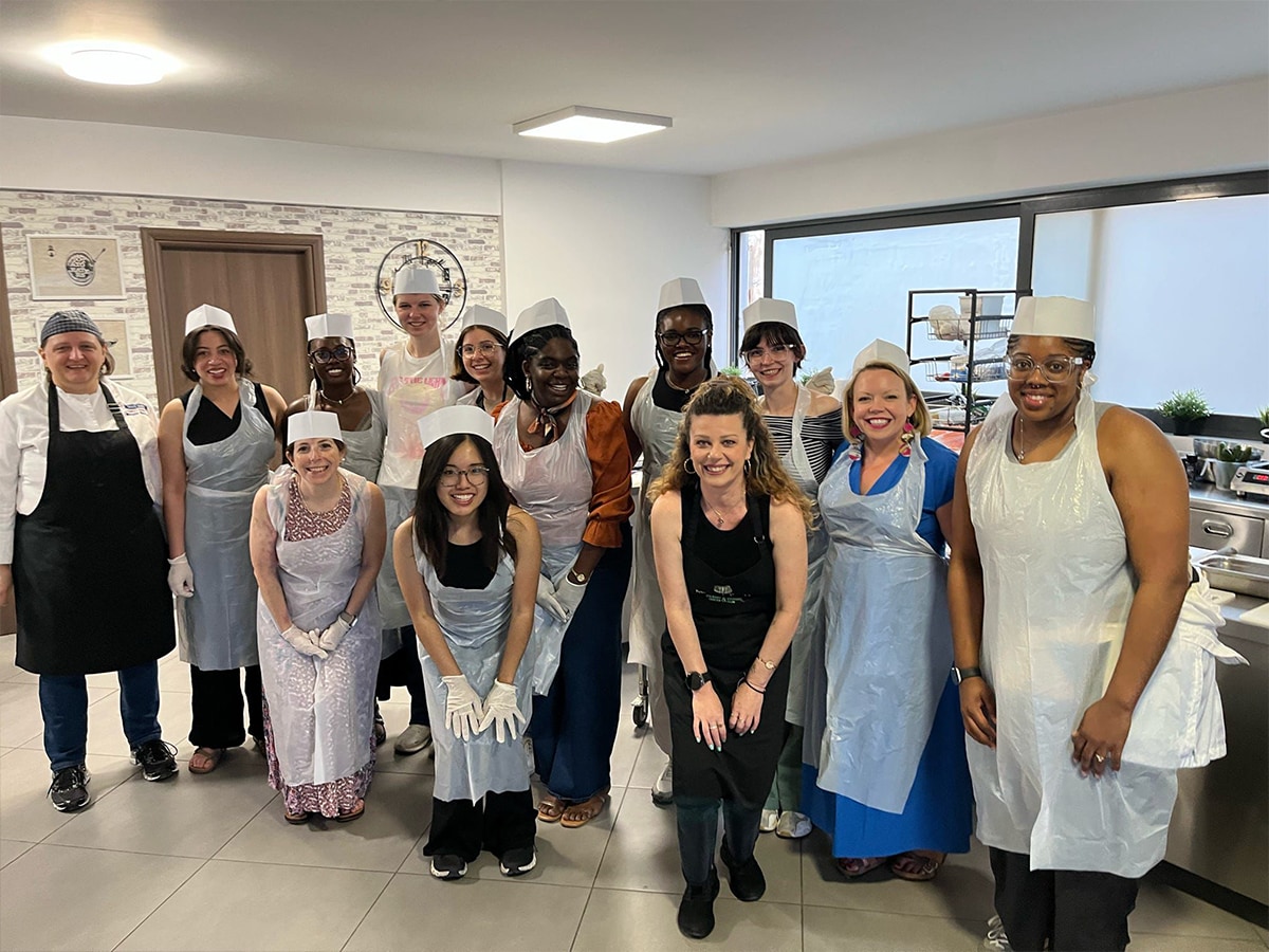 Students in aprons and hats posing in a kitchen.