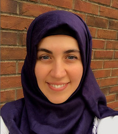 Ayse Zengul smiling, wearing a royal purple headscarf. 