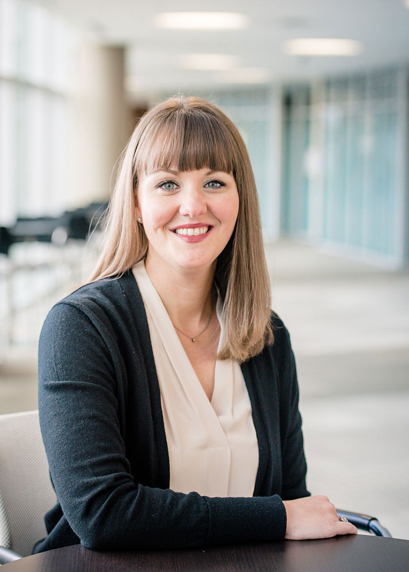 Dr. Wingo has long, light brown hair with bangs. She sits at a table, wearing a white blouse and black cardigan. 