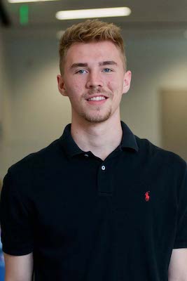 Stephen Lanzi has short blond hair, mustache, and goatee, and is wearing a black polo shirt. 