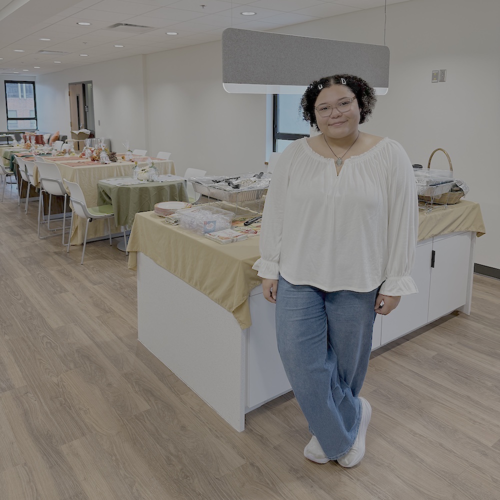 Angelica Vercher poses in front of the Thanksgiving tables and decorations