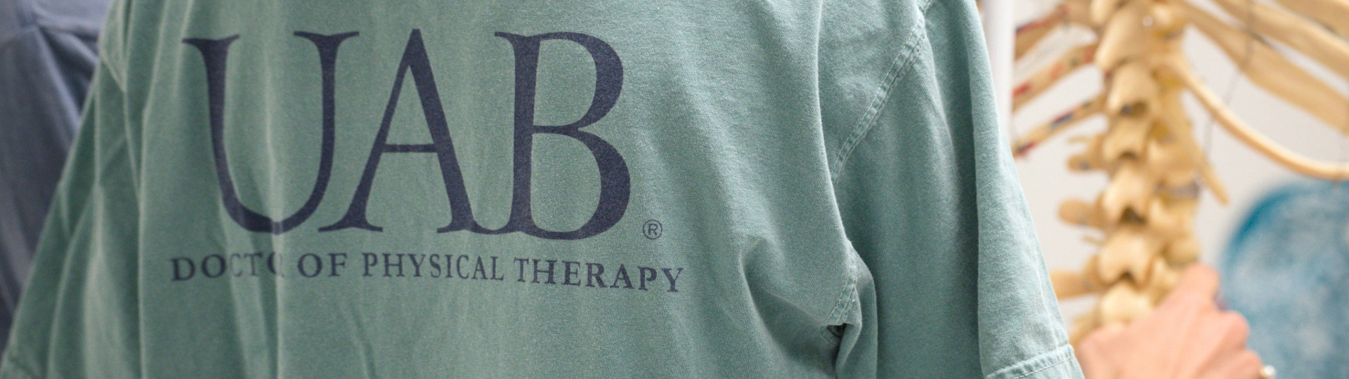 Picture of a student inspecting the spine of a classroom skeleton