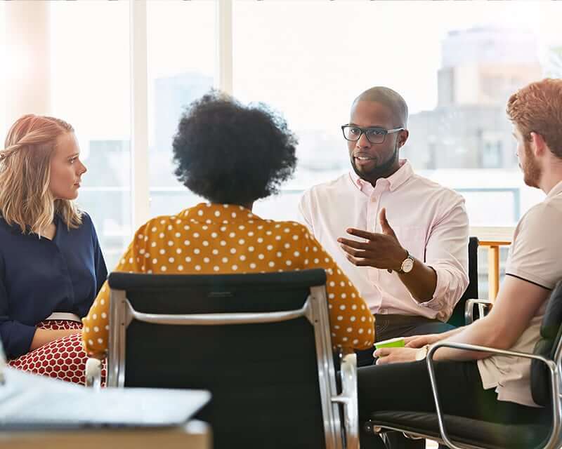 A diverse group of people talking around a table. 