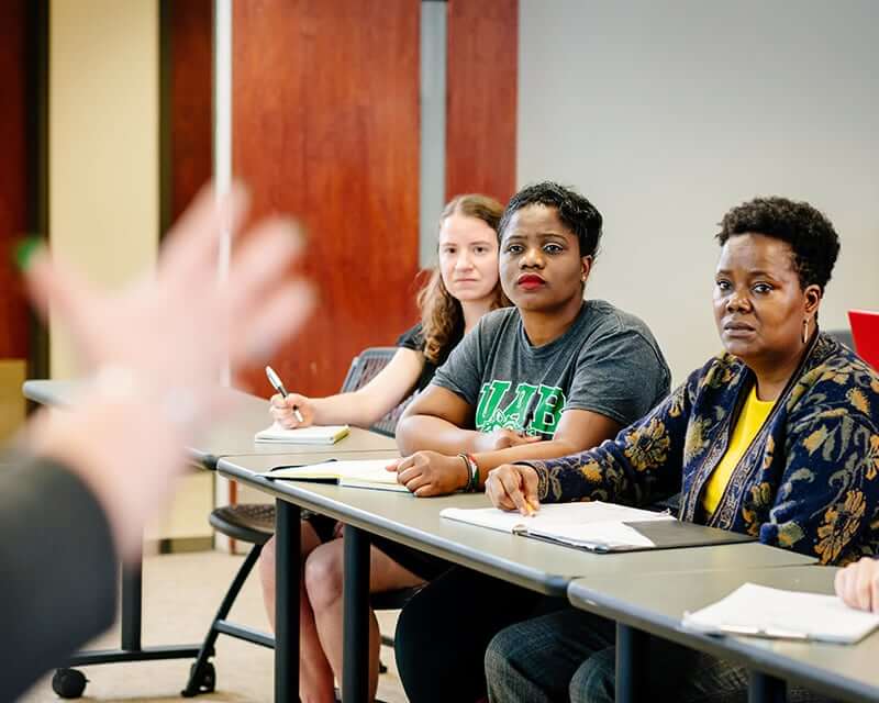 Graduate students listening to a professor. 