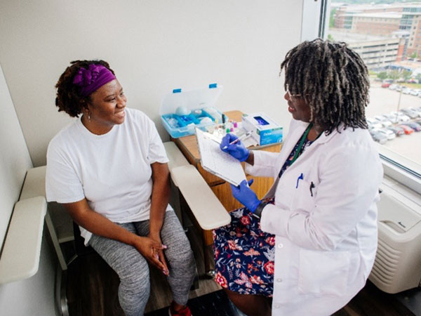 A Black female doctor talks to a Black female studey participant. 