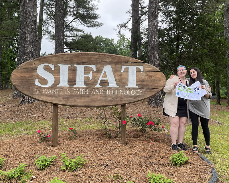 Students standing in front of the SIFAT sign.