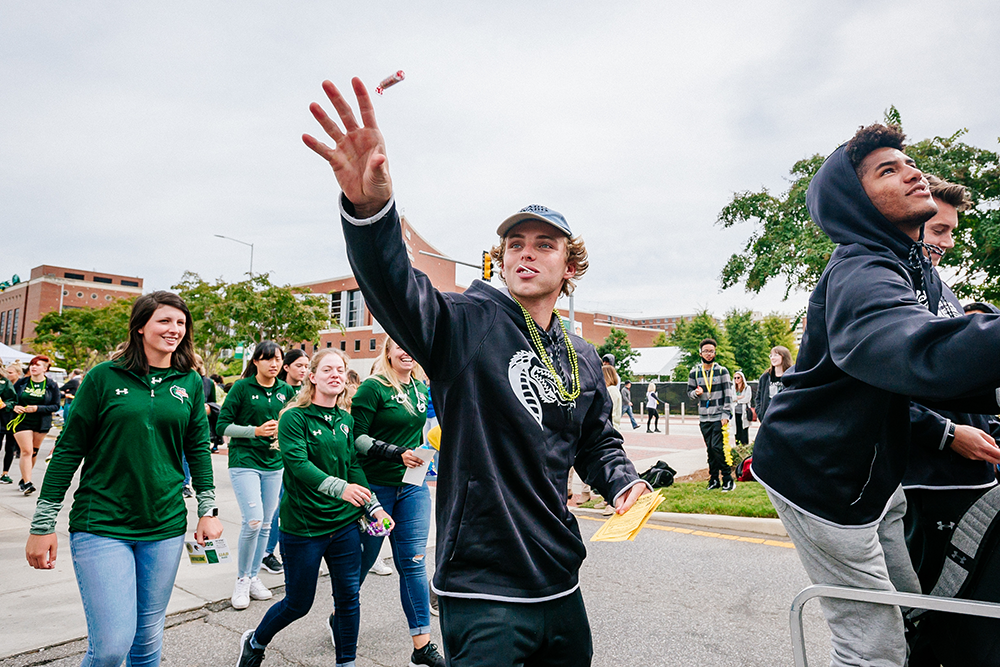 students waving in homecoming parade