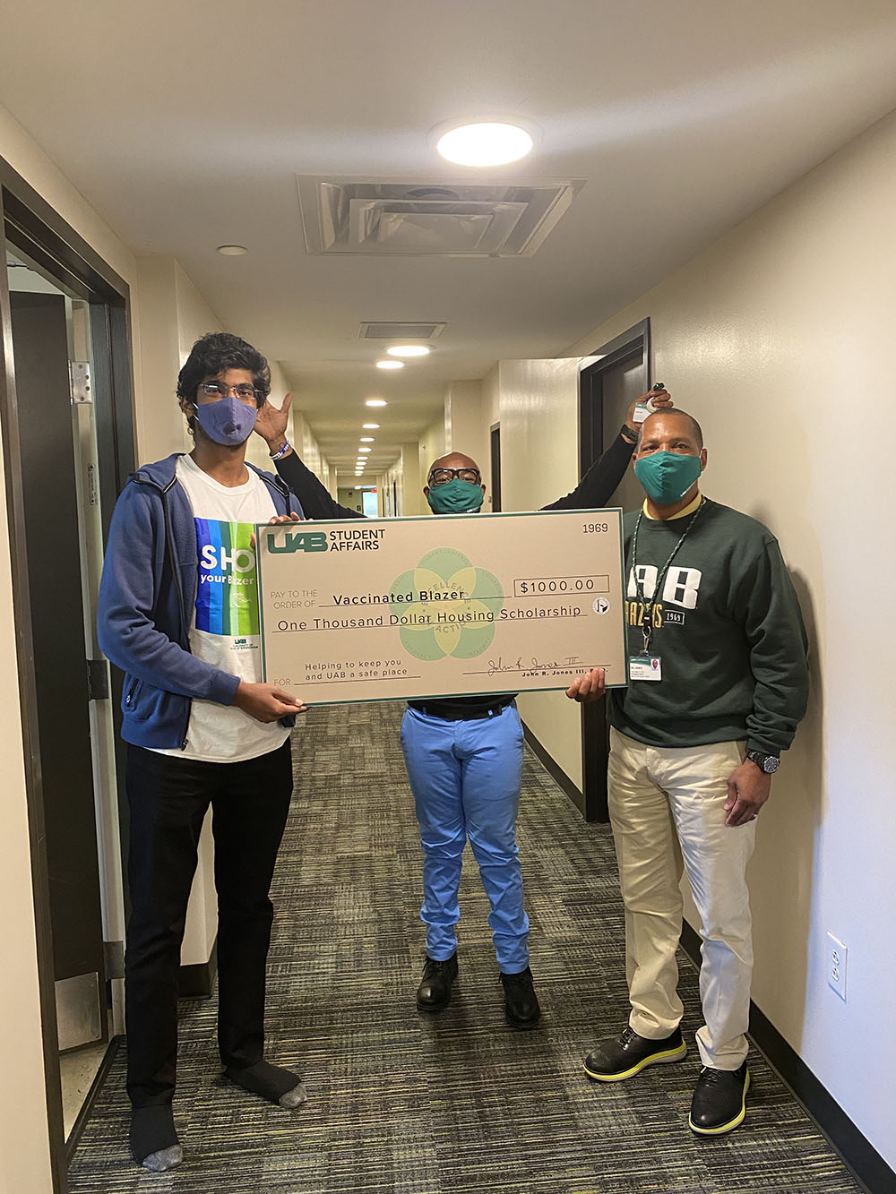 John Jones III, PhD holding check with scholarship recipient, Brian Johnson Director of Housing and Residence Life is posing in the backgroudn