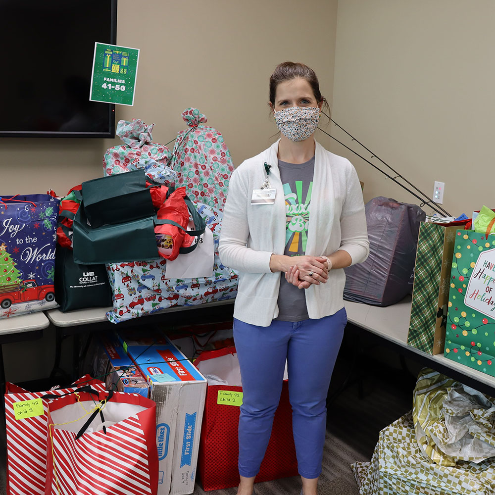 Meredith Kahl, director of Off-Campus Student and Family Engagement, standing amongst a pile of donated presents