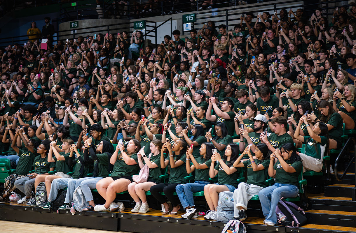 Large group of students holding up their cell phones as if to take a selfie