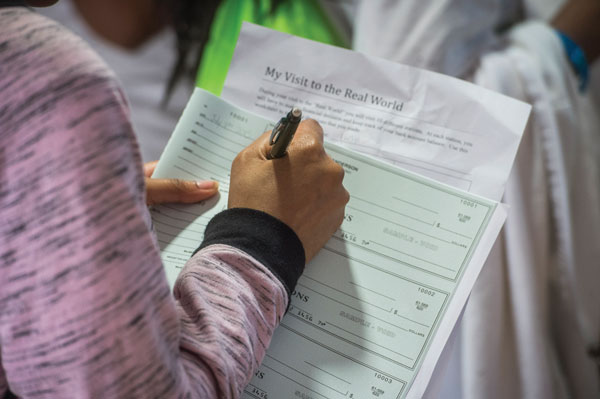 Image of a hand signing a check.