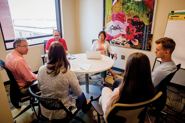 Group of UAB faculty and students sitting around a table talking.