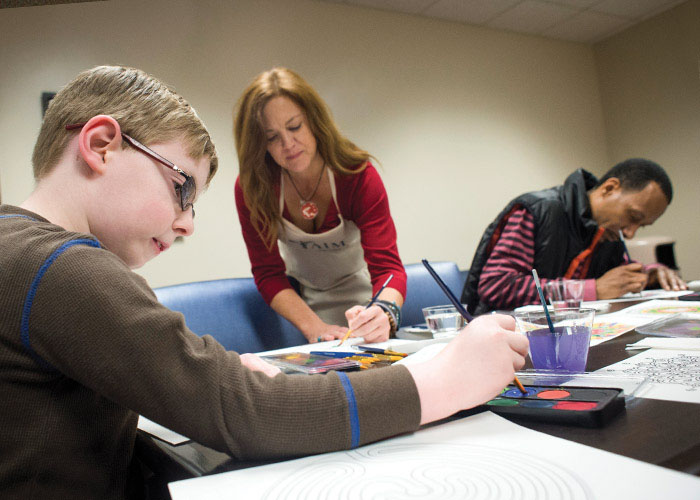 Photo of Kim McKenzie painting with family members of patients