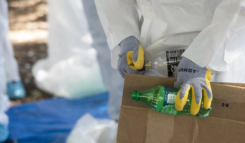 Photo closeup of student hands carrying plastic bottles and cardboard