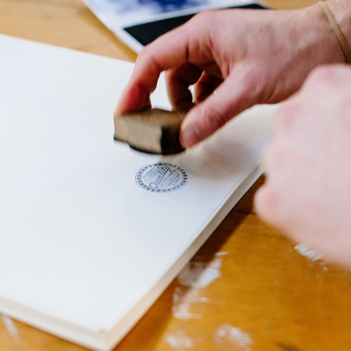 Closeup photo of Brett Forsyth using a 'Quality' stamp ont the back of a finished poster