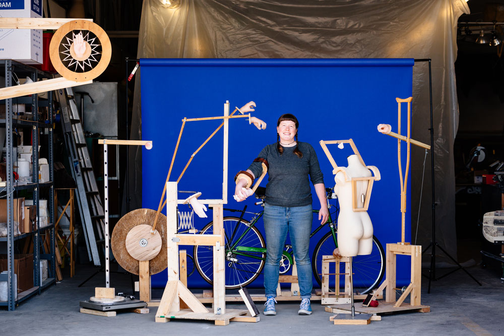 Photo of Stacey Holloway in garage surrounded by her sculptures and the materials used to make them