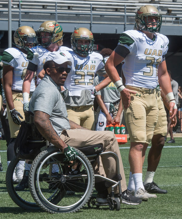 Photo of Timothy Alexander working with players in uniform at Legion Field