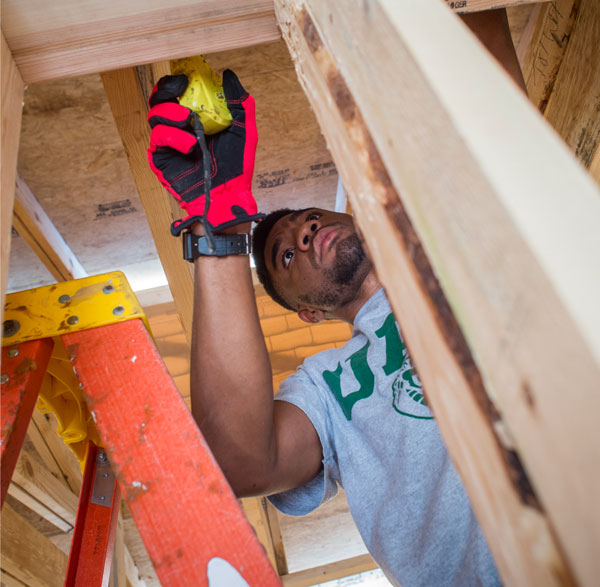 Photo of student measuring beams of house during construction