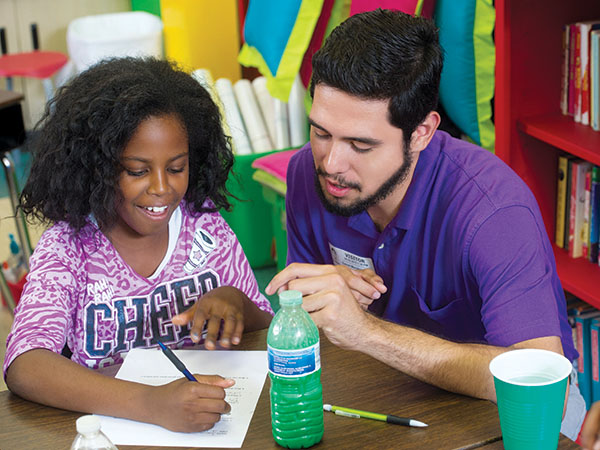 Photo of Daniel Mendoza with student at desk