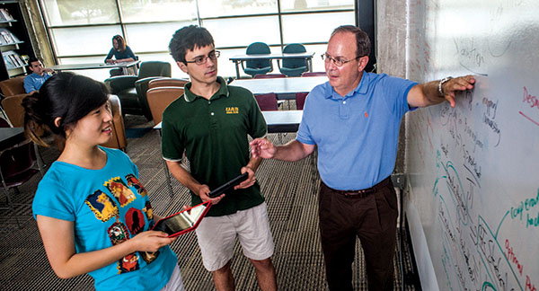 Photo of Joel Dobbs talking with students at whiteboard