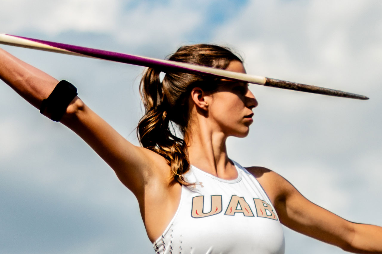 Close-up of a female student-athlete is throwing a javelin at the UAB Track and Field Facility.