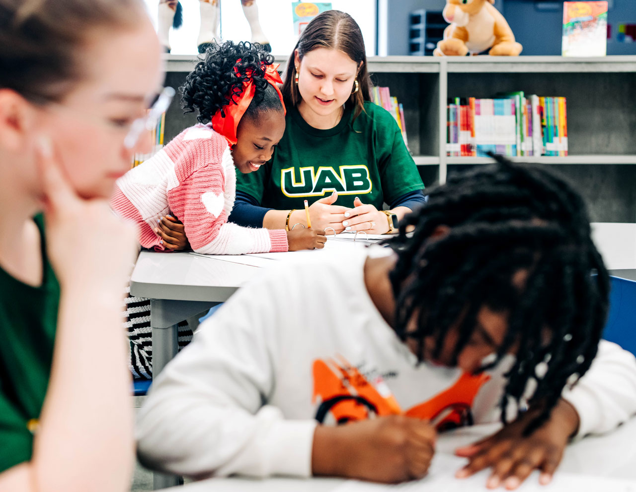 Volunteer helps a young child during a classroom activity.