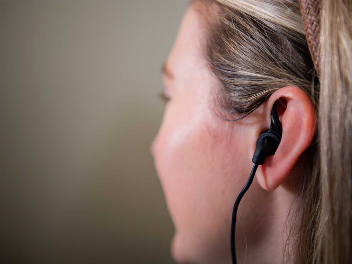 Closeup of a black taVNS earbud inserted into the ear of a mock research participant at UAB, with a cord running down to the taVNS control device (not shown).