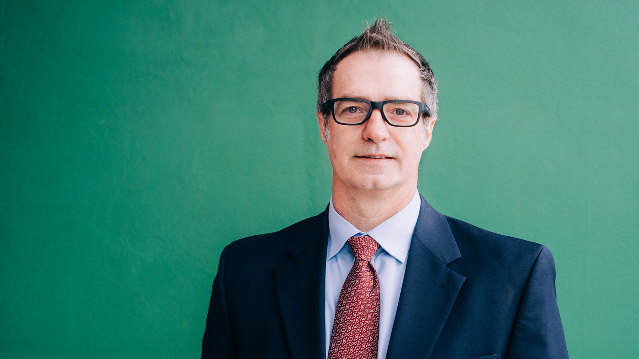 Portrait of William Jamie Tyler, Ph.D., wearing a suit and tie against a green background.