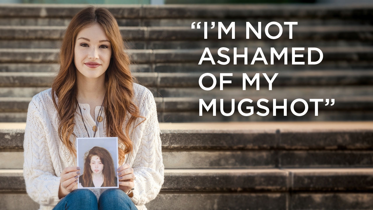 Photo of Anna Alford on steps holding her mugshot; headline: I&#039;m Not Ashamed of My Mugshot