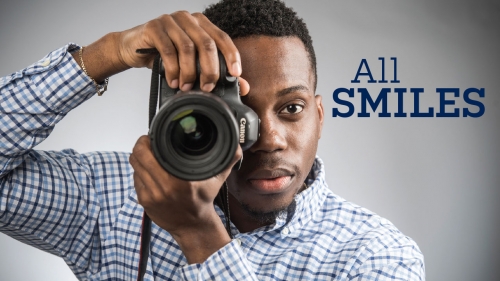 Closeup of Mark Abere aiming camera at viewer; headline: All Smiles